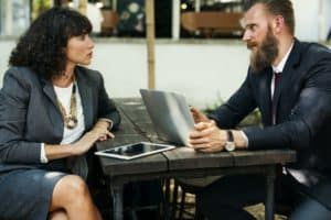 businessman and businesswoman talking with ipad and macbook