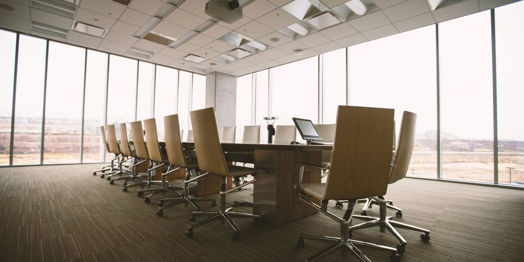 oval brown wooden conference table and chairs inside conference room