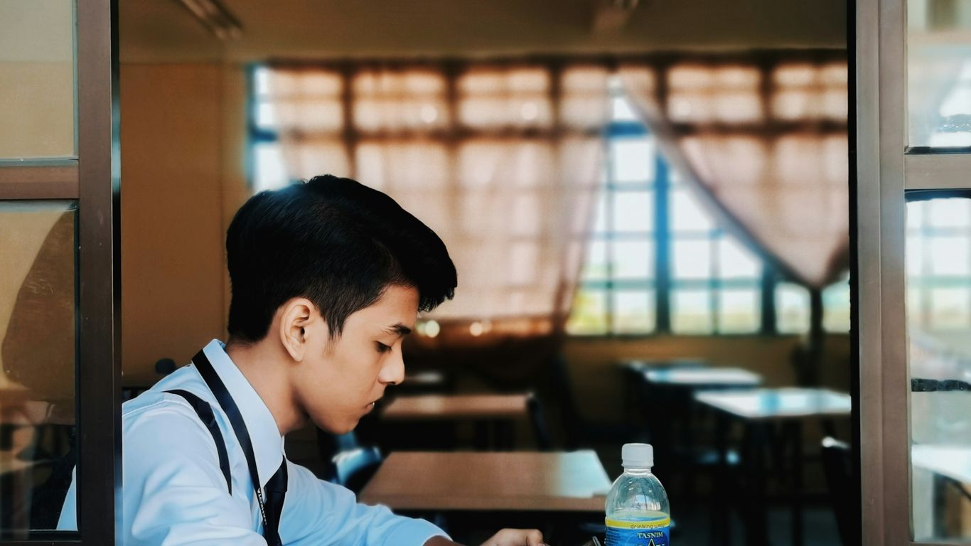 man in white and black shirt sitting at the table