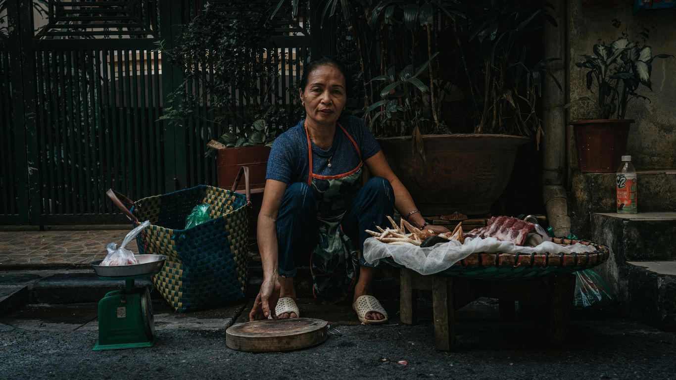 A woman sells food on a sidewalk.