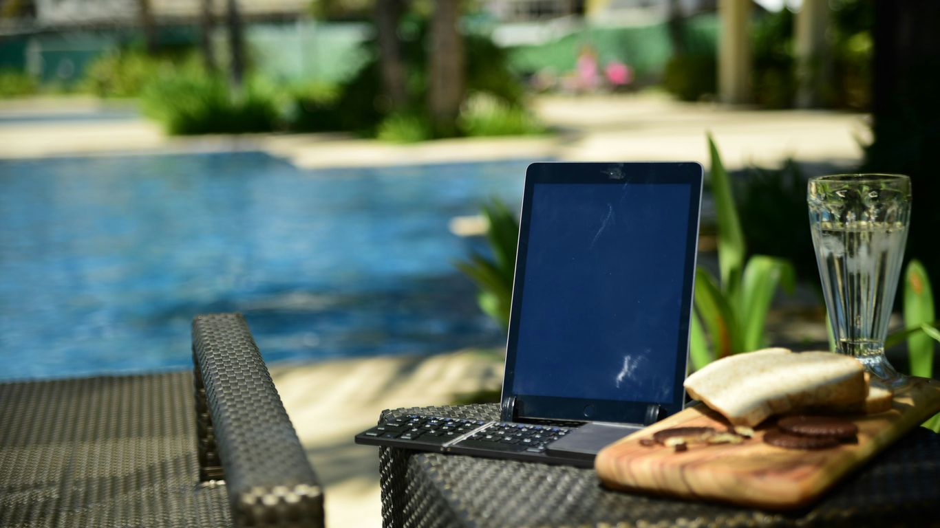 a laptop computer sitting on top of a table next to a pool