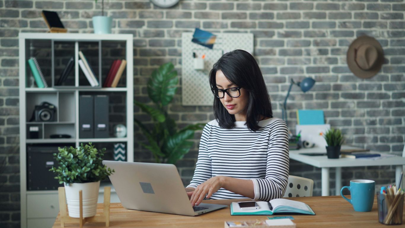 a woman sitting at a table using a laptop computer