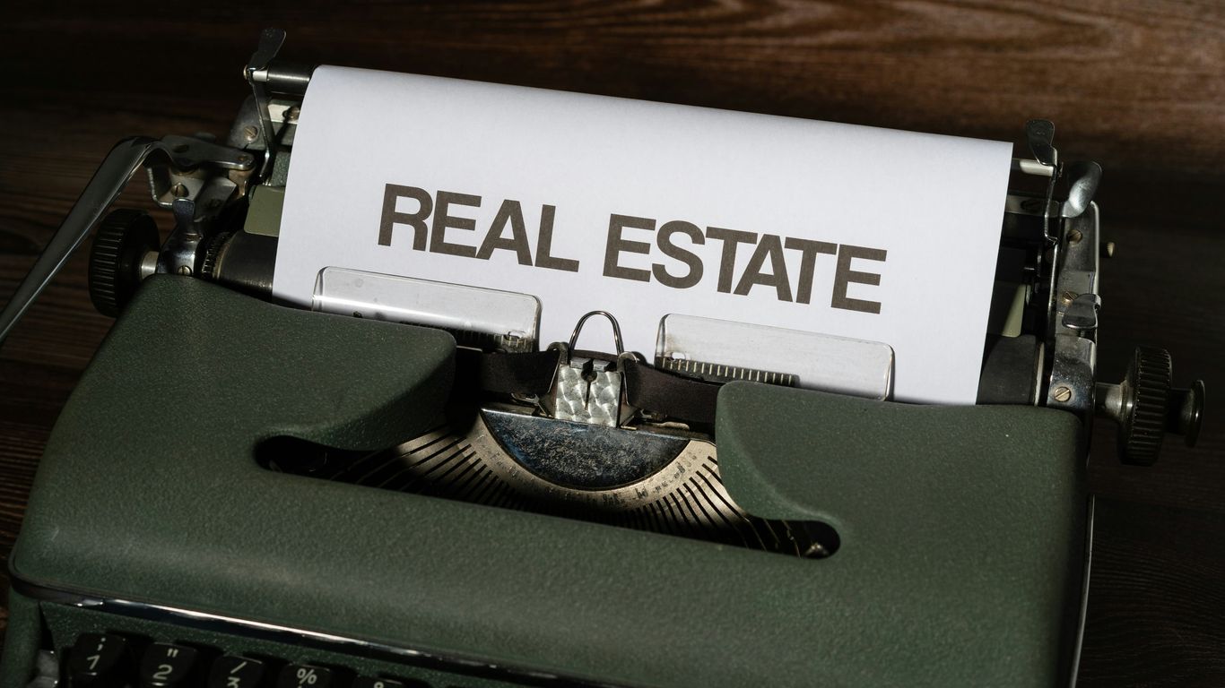 a close up of a typewriter with a real estate paper on it