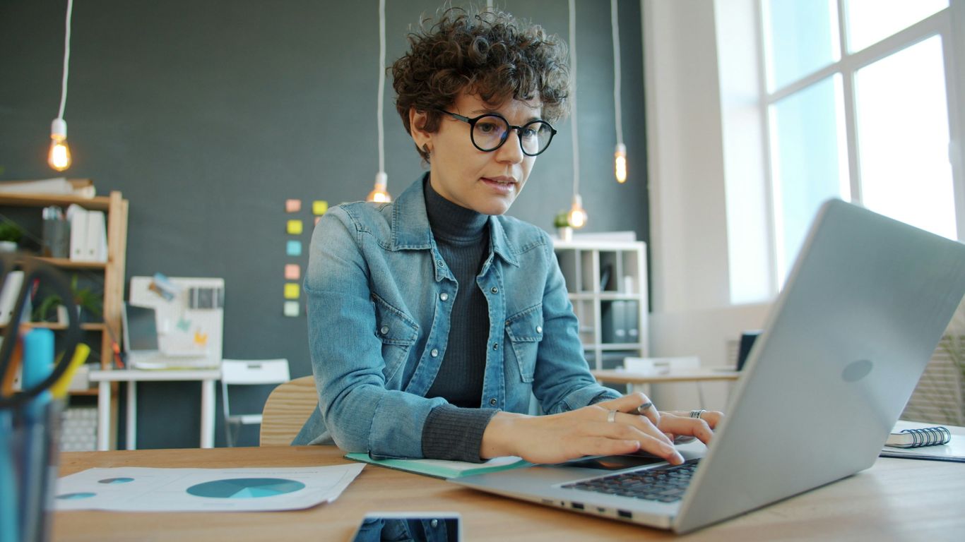 Woman working on a laptop in a modern office.