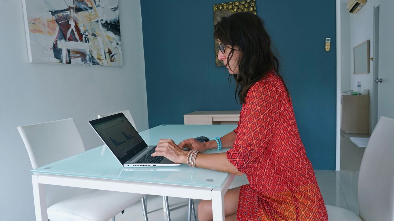 Woman works on laptop at a table.