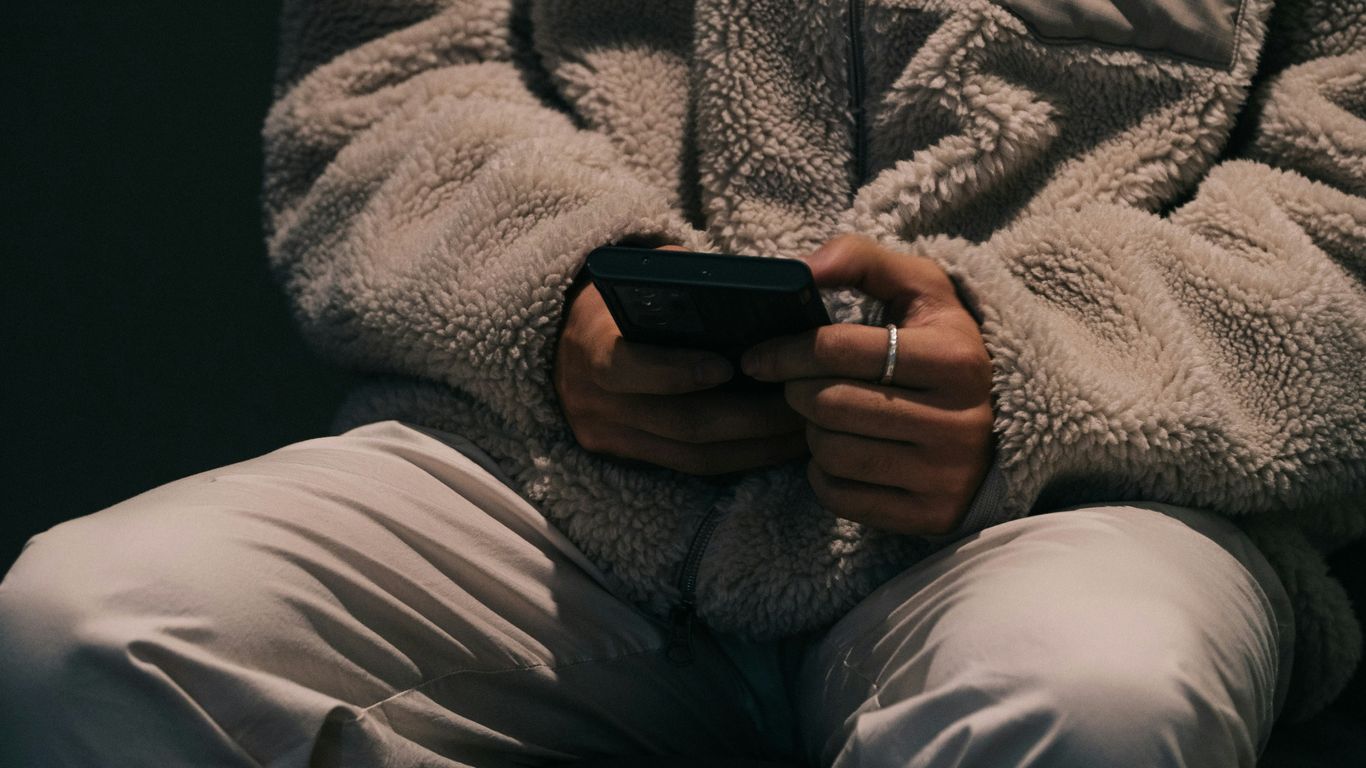 a person sitting down holding a cell phone