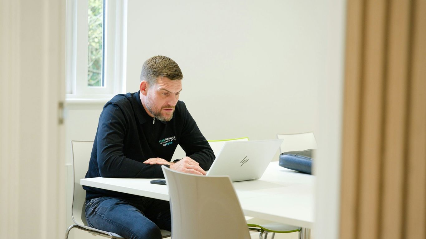 Man working on laptop at a white table.