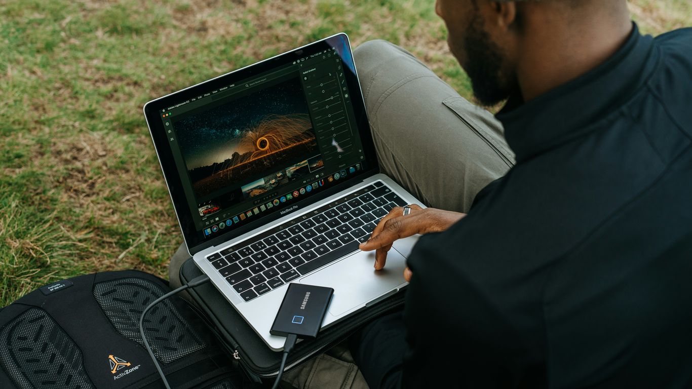 man in black jacket using macbook pro
