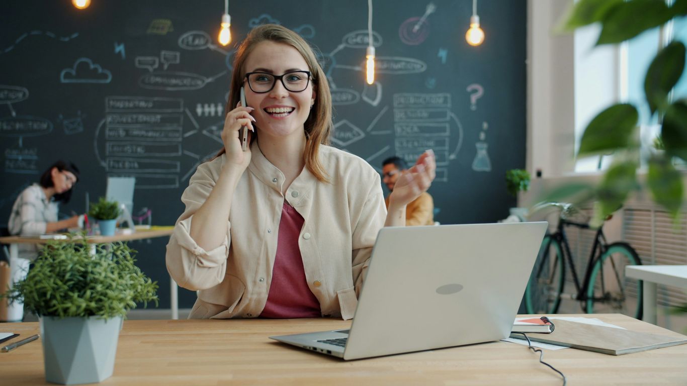 Smiling woman talking on phone in modern office.