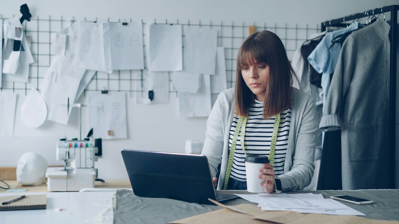 Fashion designer working on her laptop and sipping coffee.