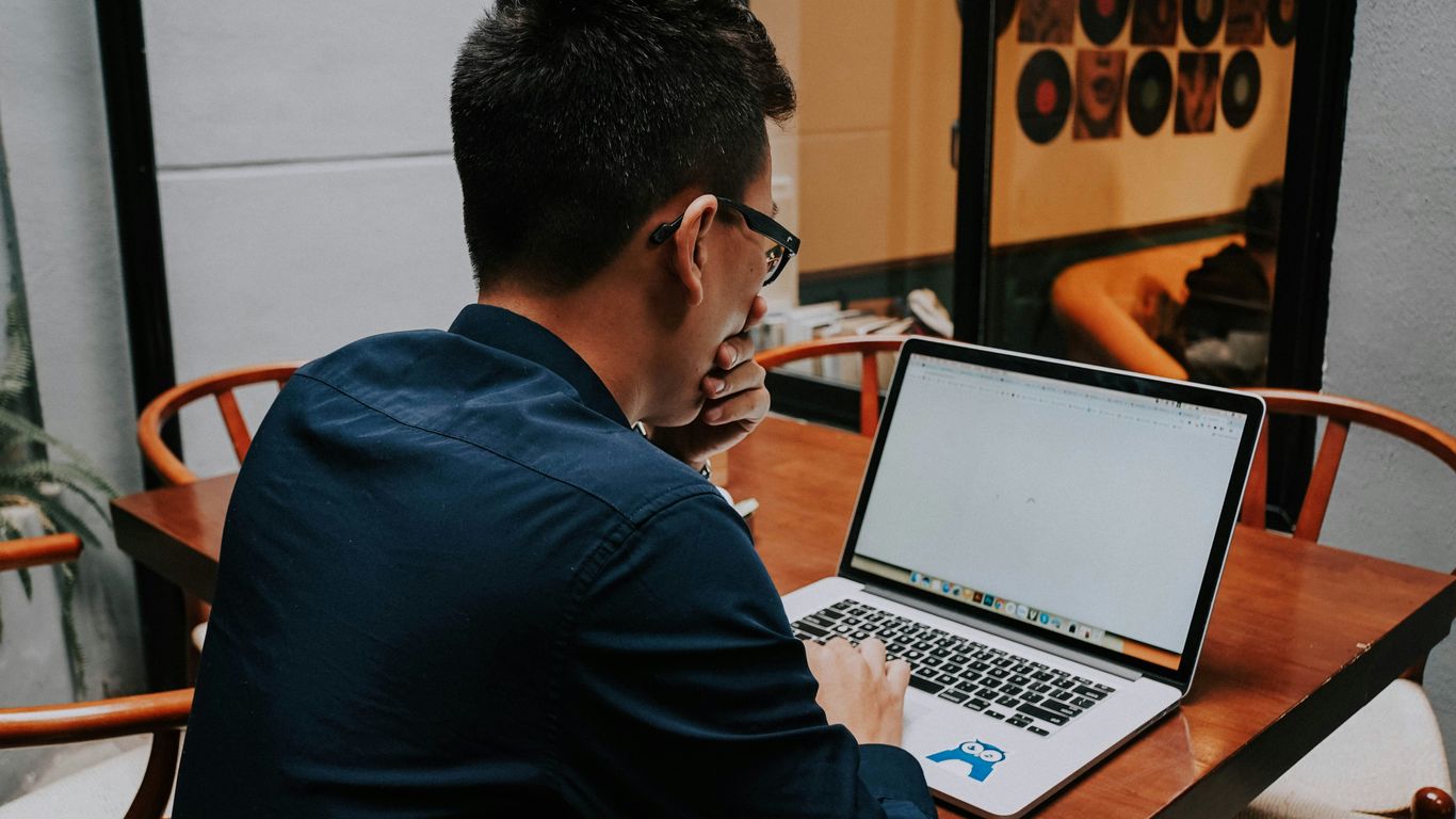 a man sitting at a table using a laptop computer